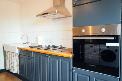 a kitchen with blue cabinets and a stove top oven at Bradley's Hideaway With Private Garden in Eccleston