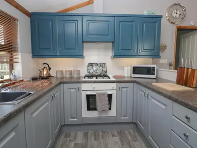 a kitchen with blue cabinets and a stove at Sunset Retreat in Carnforth