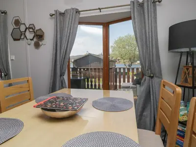 a dining room table with chairs and a window at Sunset Retreat in Carnforth