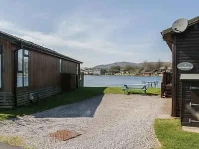 a building with a bench next to a lake at Sunset Retreat in Carnforth