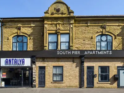 an old brick building with a clock on top of it at South Pier Apartment in Blackpool