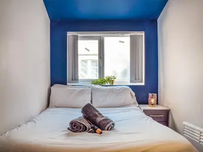 a bedroom with blue walls and a bed with blankets at South Pier Apartment in Blackpool