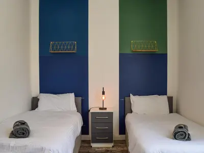two beds in a room with blue and green at South Pier Apartment in Blackpool
