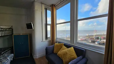 a room with a couch and a large window overlooking the ocean at 6 Cocker Square in Blackpool