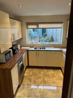 a kitchen with a sink and a washing machine at Night Owl Cottage in Rainford