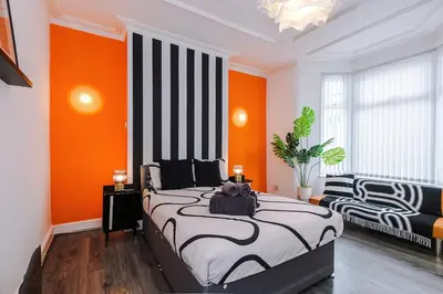 a bedroom with a large bed with an orange wall at #17 Walk to Anfield Stylish House for 12 in Liverpool