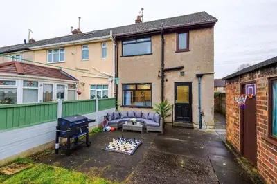 a backyard with a grill and chessboard in front of a house at New 2 Bed House - Perfect for Contractors & Families In St Helens Weekly & Monthly Stays in Saint Helens