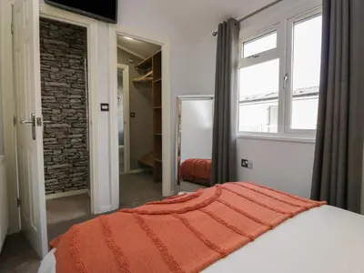 a bedroom with a bed with an orange blanket on it at Gressingham View Lodge in Carnforth