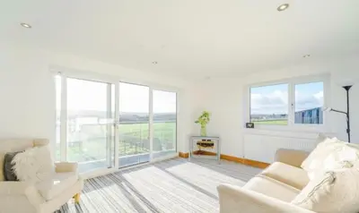 a white living room with a couch and windows at Oswaldtwistle Farmhouse in Oswaldtwistle