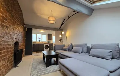 a living room with couches and a brick wall at Stylish City Centre Apartment With Parking in Preston