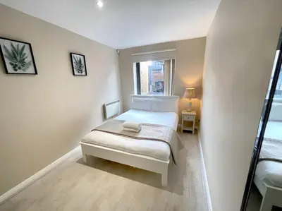 a small white bedroom with a bed and a window at 2BR City Centre Apt - Balcony - Sleeps 6 in Liverpool
