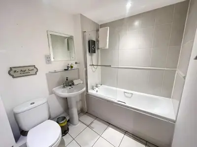 a white bathroom with a toilet and a tub and a sink at City Centre 2BR Apartment, Free Parking! in Liverpool