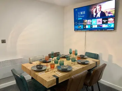 a dining room with a table with chairs and a tv at Three-Bedroom Superior Apartment - Sleeps 6 in Southport