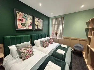 a bedroom with two beds and a green wall at Full Private House Sleeping 26 in Blackpool