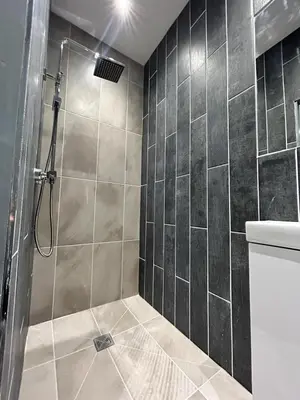 a bathroom with a shower with a tile wall at Full Private House Sleeping 26 in Blackpool