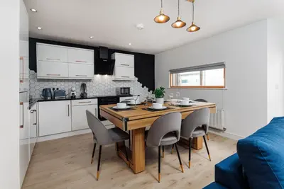 a kitchen and dining room with a wooden table and chairs at Flatzy - Prime City Apartment with Free Parking & Ping Pong Table in Liverpool