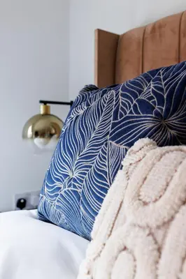 a blue and white pillow on a bed with a blanket at Flatzy - Prime City Apartment with Free Parking & Ping Pong Table in Liverpool