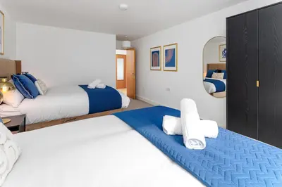 a bedroom with two beds with blue and white at Flatzy - Prime City Apartment with Free Parking & Ping Pong Table in Liverpool