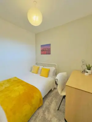 a bedroom with a bed with yellow pillows and a desk at Room 5 Shared House in L6 in Liverpool