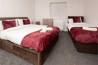 a bedroom with two beds with red and white sheets at Central 3 Bedroom Flat w Parking in Liverpool