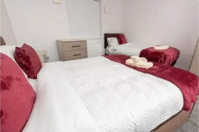 a bedroom with two beds with red and white sheets at Central 3 Bedroom Flat w Parking in Liverpool