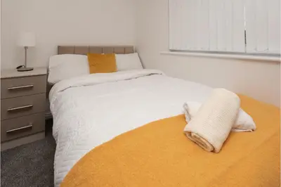 a bedroom with a bed with white sheets and an orange blanket at Central 3 Bedroom Flat w Parking in Liverpool