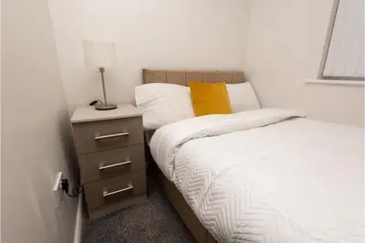 a bedroom with a bed and a night stand with a lamp at Central 3 Bedroom Flat w Parking in Liverpool