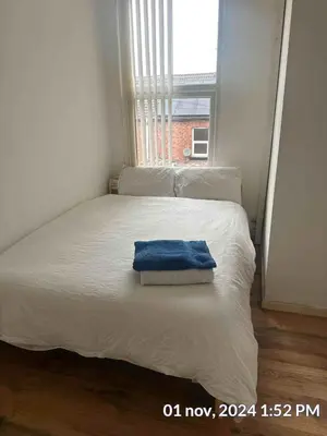 a white bed with a blue towel on top of it at Home in Liverpool in Liverpool