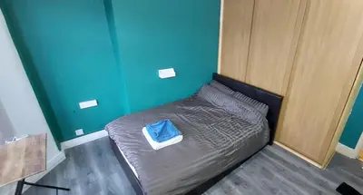 a small bed in a room with a blue wall at Home in Liverpool in Liverpool