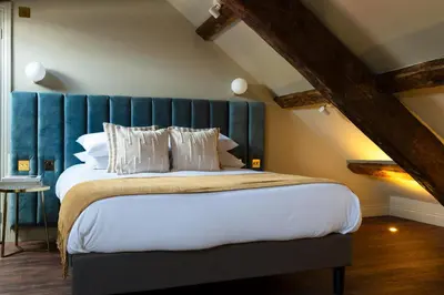 a bedroom with a large bed with a blue headboard at Domain Boutique Rooms in Lancaster