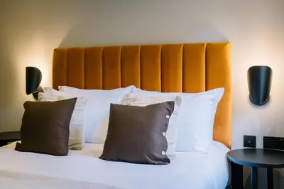 a bed with white pillows and an orange headboard at Domain Boutique Rooms in Lancaster