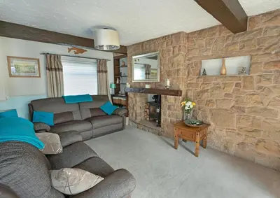 a living room with a couch and a stone wall at Smithy Cottage in Heysham