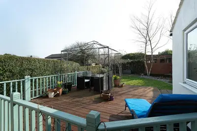 a patio with a grill and chairs on a deck at Smithy Cottage in Heysham
