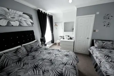 a bedroom with a bed and a bed and a window at Rossall Guest House Blackpool - Ideal For Families & Couples in Blackpool