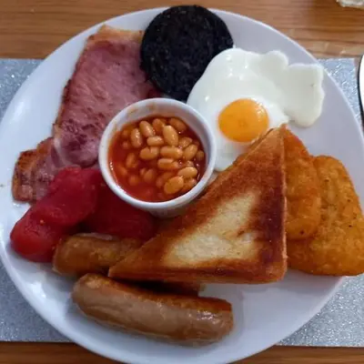 a plate of breakfast food with eggs sausage beans and toast at Rossall Guest House Blackpool - Ideal For Families & Couples in Blackpool