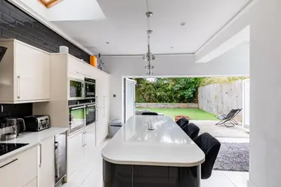 a kitchen with white cabinets and a table and chairs at Lux nights away in Cleveleys