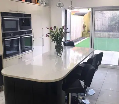 a kitchen with a large white counter with chairs at Lux nights away in Cleveleys