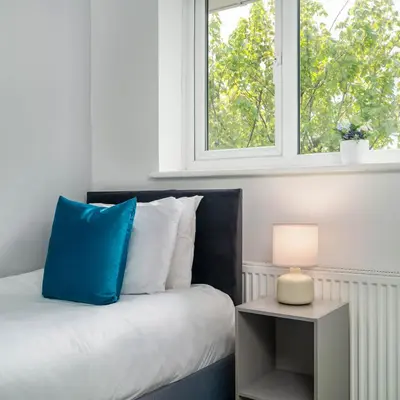 a bedroom with a bed with a blue pillow and a window at The Acorn Nook - Central Stay in Liverpool