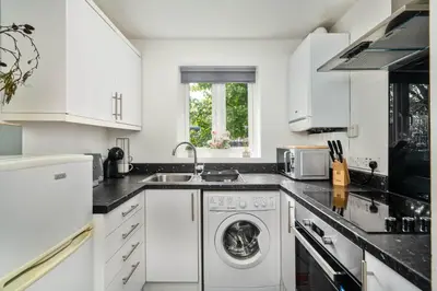 a kitchen with white cabinets and a washer and dryer at The Acorn Nook - Central Stay in Liverpool