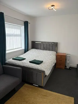 a bedroom with a bed and a couch and a window at Liberty Guest House in Liverpool