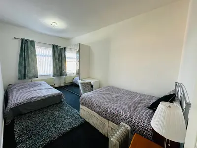 a small bedroom with two beds and a lamp at Liberty Guest House in Liverpool