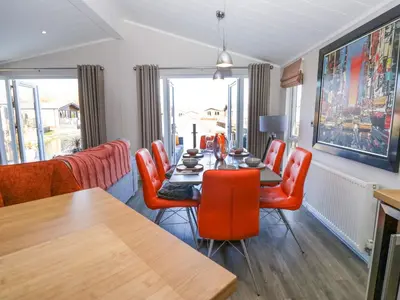 a dining room with a table and orange chairs at Coniston View Lodge in Carnforth