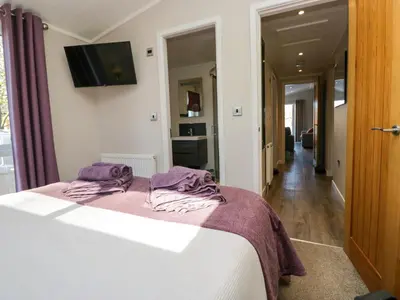 a bedroom with a bed and a tv on the wall at Coniston View Lodge in Carnforth