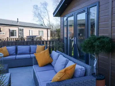 a patio with a blue couch and yellow pillows at Coniston View Lodge in Carnforth
