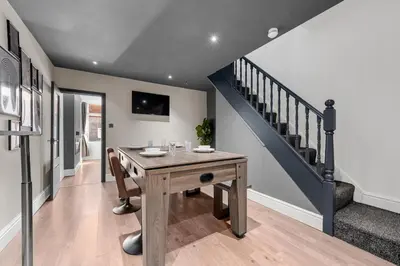 a dining room with a wooden table and stairs at Bolton Retreat Modern 3BR Home Pool Table & Parking Sleeps 6 in Bolton