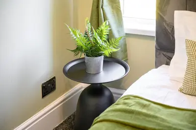 a black table with a plant on it next to a bed at Bolton Retreat Modern 3BR Home Pool Table & Parking Sleeps 6 in Bolton