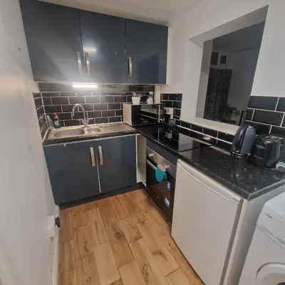 a kitchen with black cabinets and a wooden floor at Ground Floor Holiday flat in Blackpool