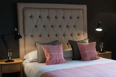 a bed with pink and grey pillows and two lamps at Derby Arms in Longridge