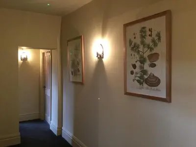 a hallway with two pictures on the wall and two lights at Derby Arms in Longridge