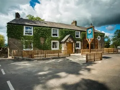 a ivy covered building with a sign in front of it at Derby Arms in Longridge